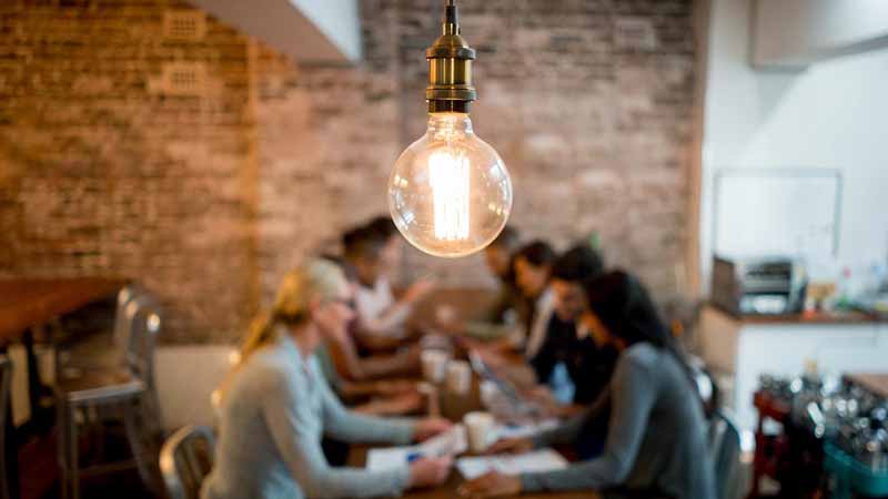 Light bulb and group of business people brainstorming at an office.