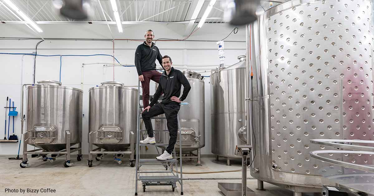 Founders of Bizzy Coffee posing next to cold brew equipment.
