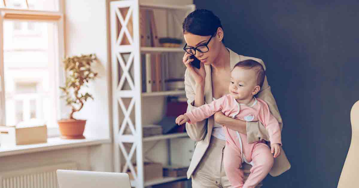 Woman entrepreneur working and holding her child.