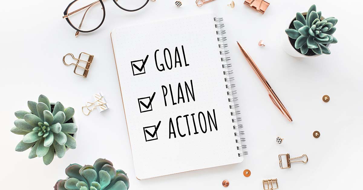 Notepad stating, Goal, Plan, Action and various office accessories.